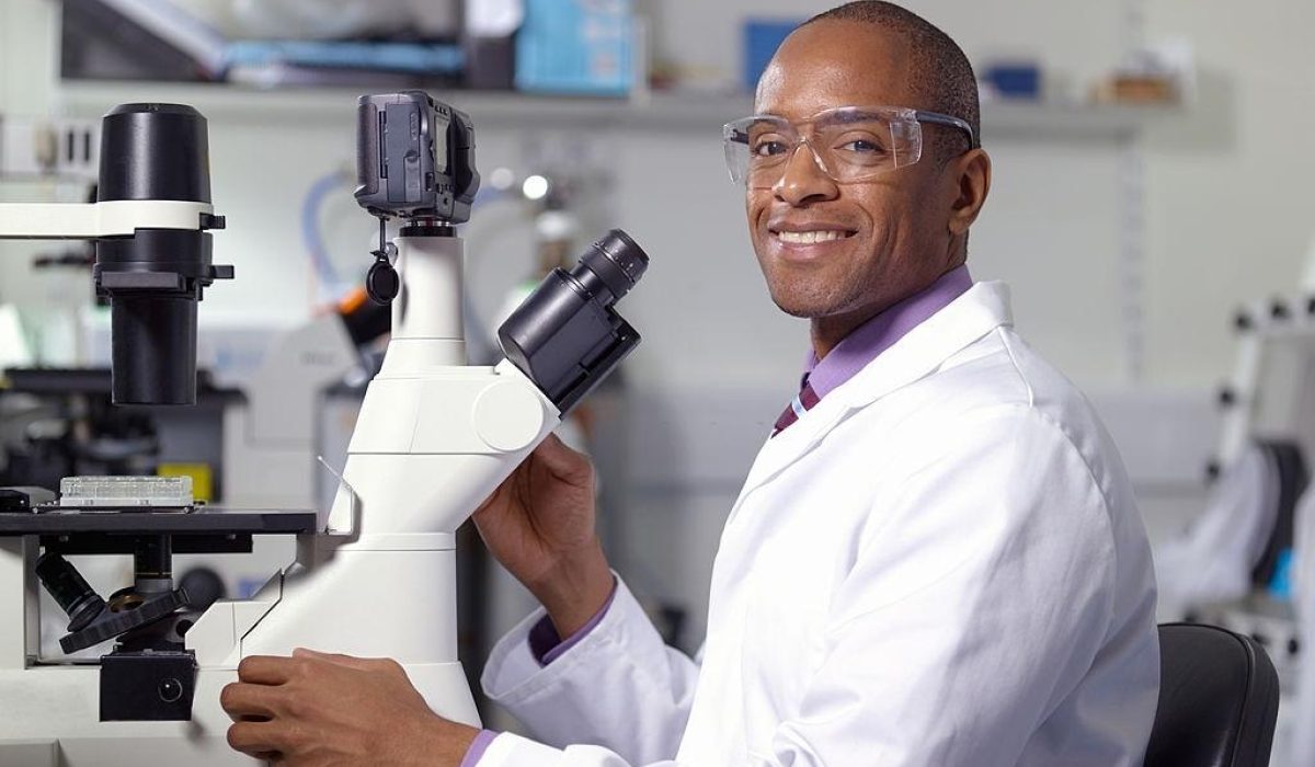 Scientist with microscope smiling